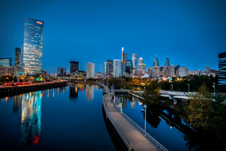 Philadelphia skyline at dusk with skyscrapers reflecting on the Schuylkill River and Schuykill Banks boardwalk.
