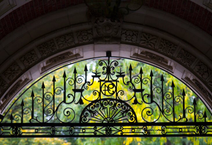 Decorative wrought iron gate under an arched stone entryway at the Quadrangle, University of Pennsylvania.